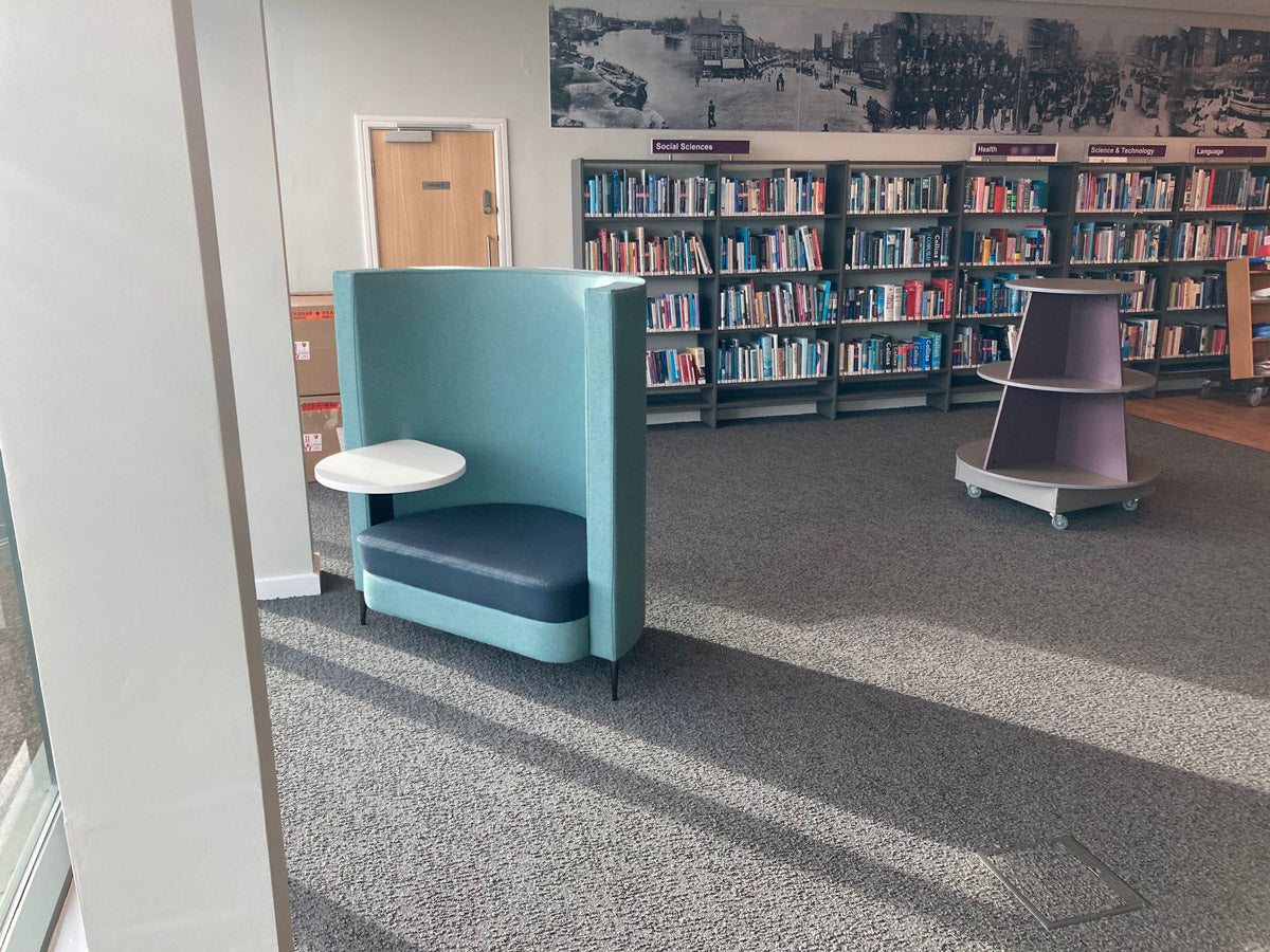 A single booth seat with white laptop table in a library