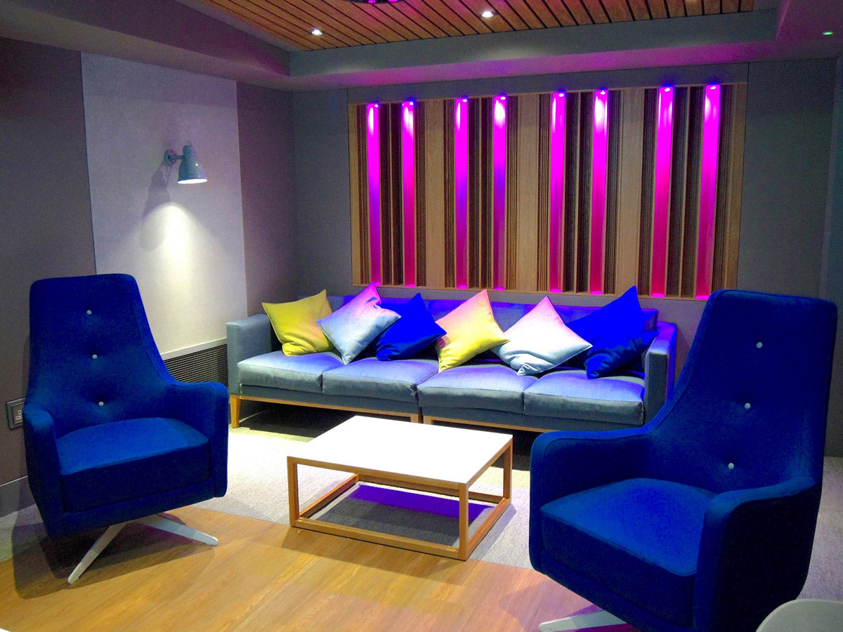 Modern living room with blue sofa, chairs, and colorful wall lights.