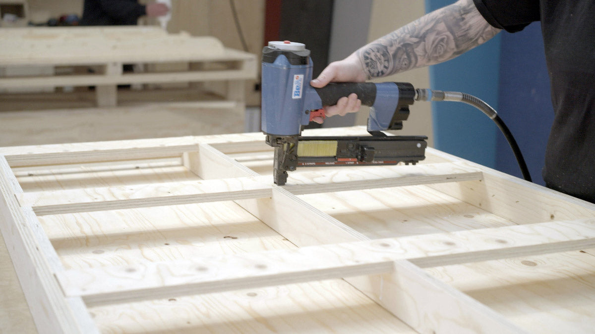 Person using a nail gun to assemble wooden furniture.