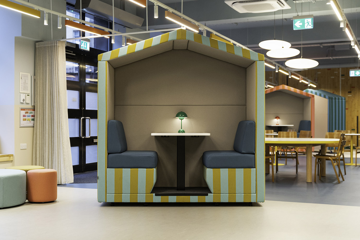 jdd bea 2 seat open front meeting pod with striped fabric and built in table. The meeting pod is on castors