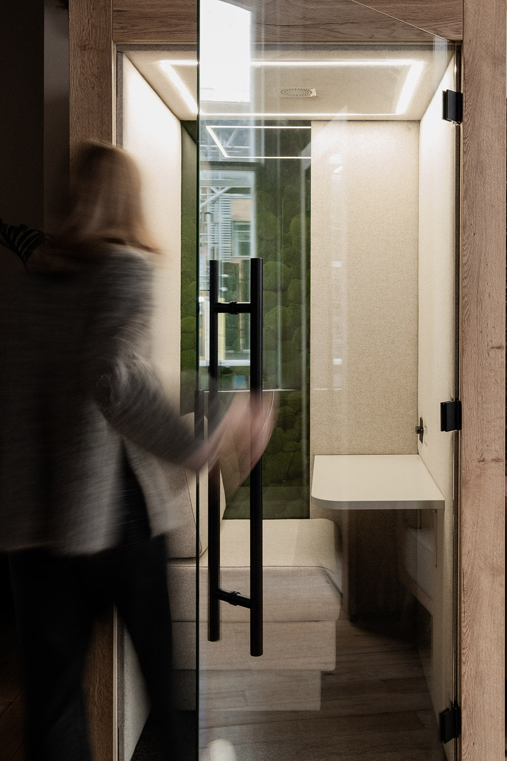 a close up of someone opening the glass door and entering the clara meeting pod