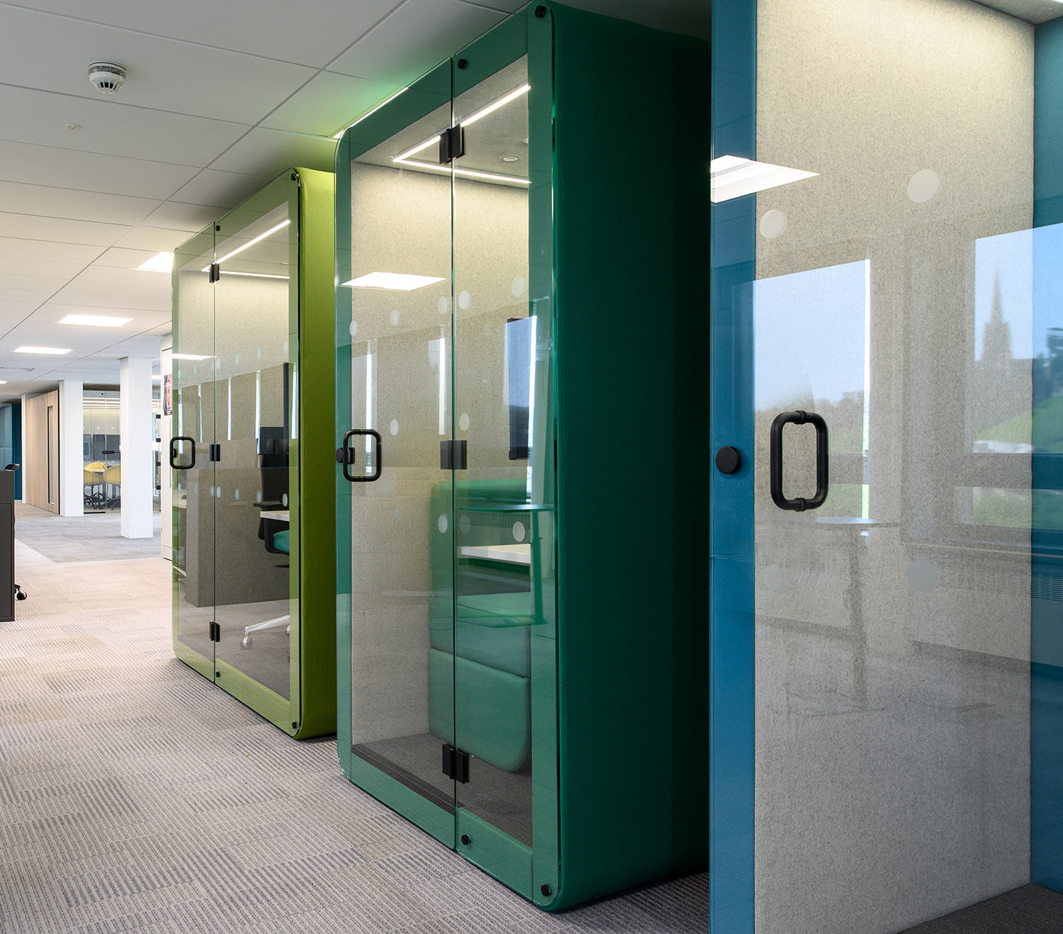 a row of jdd penelope workbooth meeting pods in green and blue