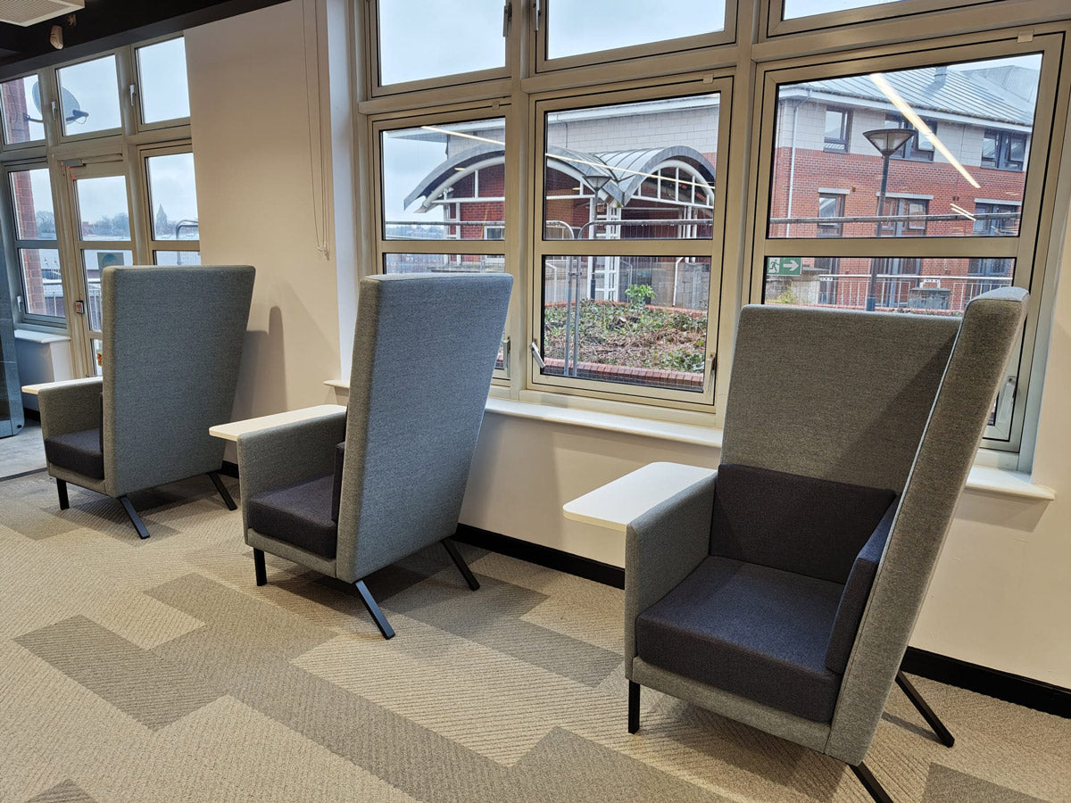 Three gray office seats in a room with large windows showing an external view.