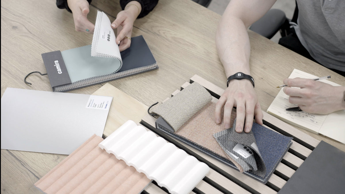 People evaluating fabric samples and a wallet on a table.